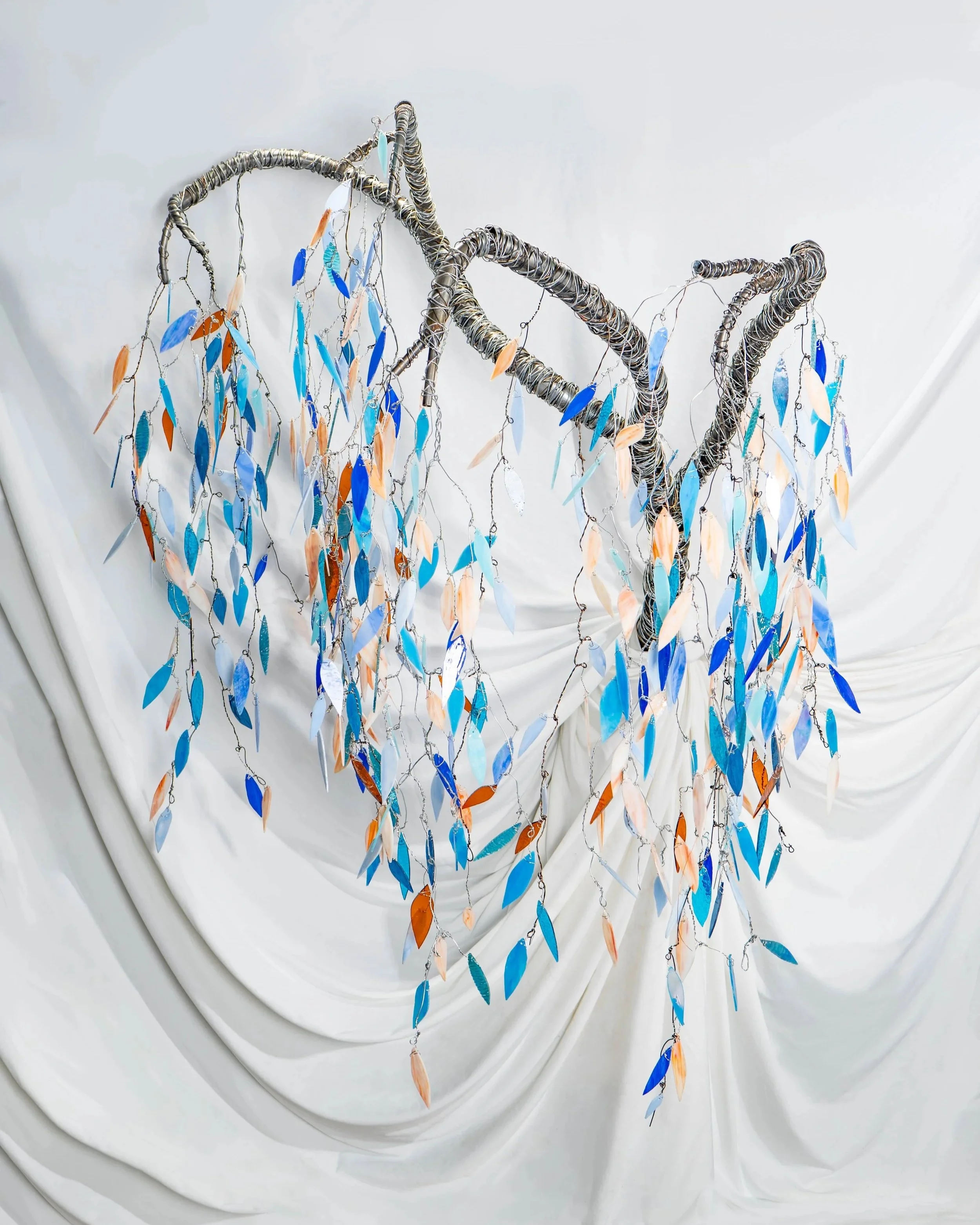 Bonnies Tree reflects the beauty of what community can grow into, each leaf representing the individuals. The light passing from one leaf to the next is like information or resources traveling from person to person. 
Stained glass, Steel, Wire sculpt