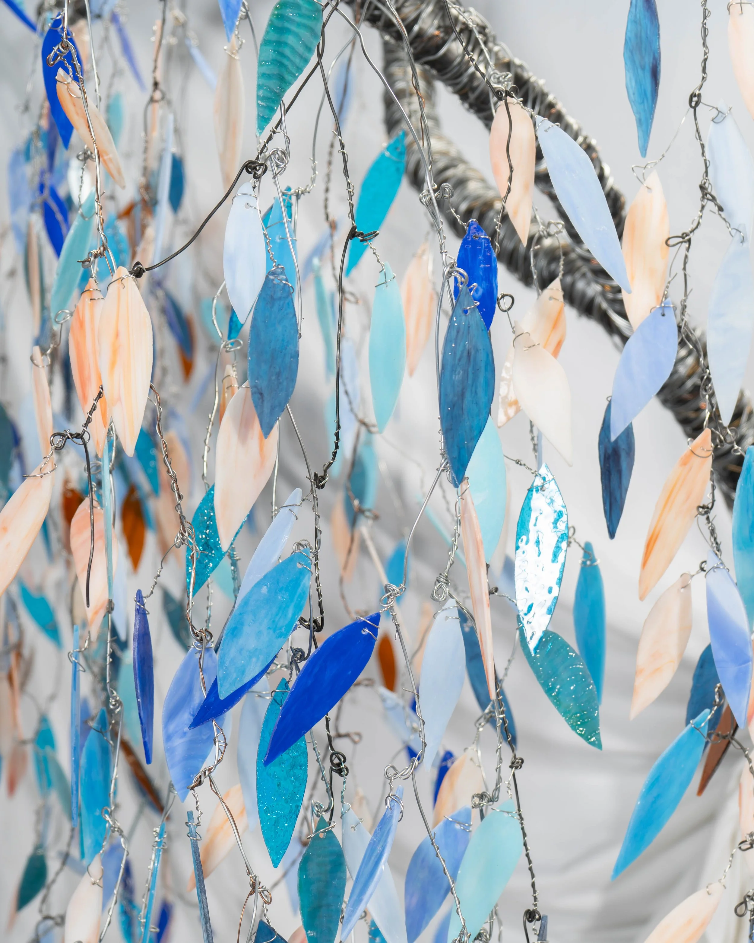 Multiple blue, turquoise, white, and peach seashells hanging on metal chains.