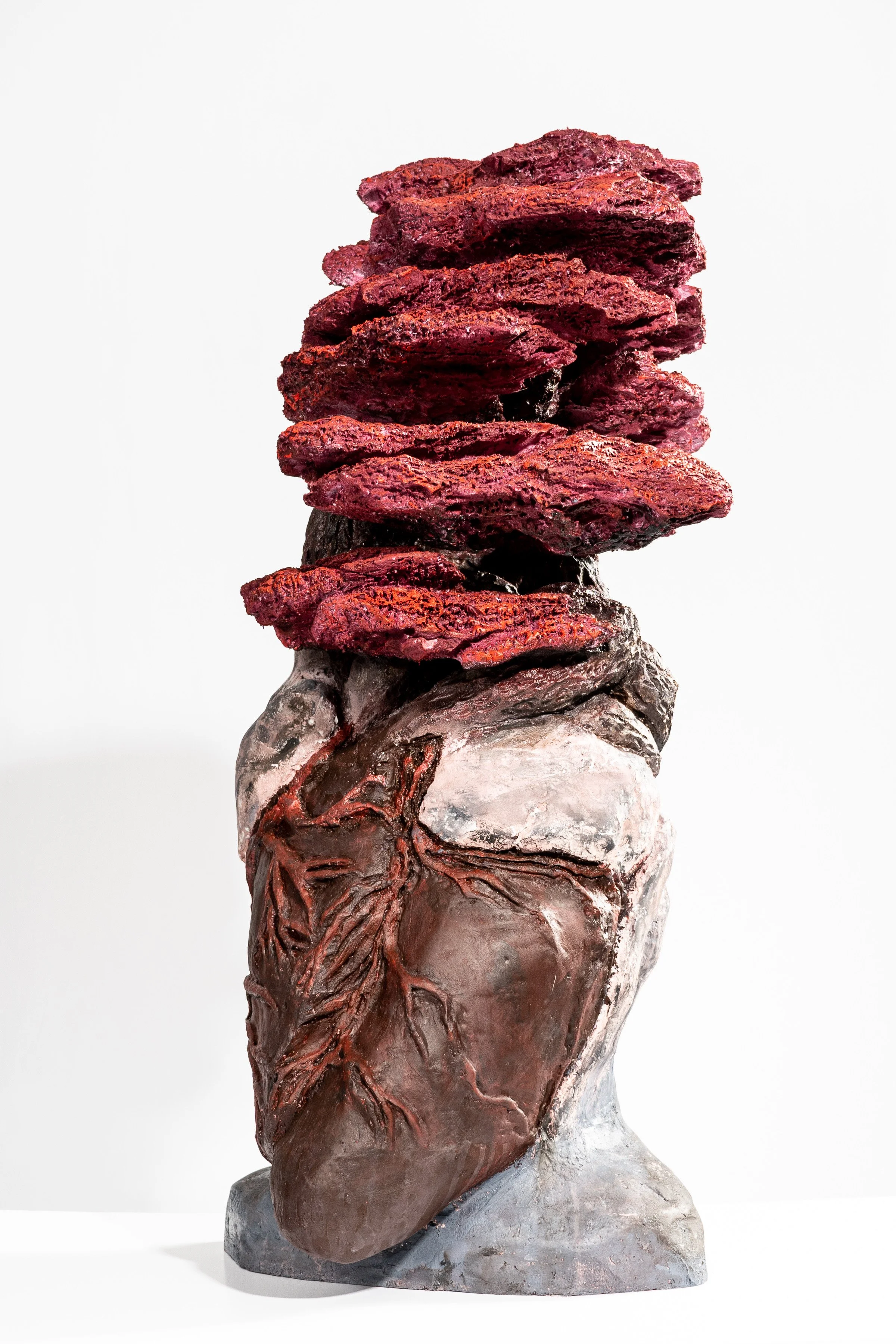 Sculpture of a human heart with red and black textured stones stacked on top.