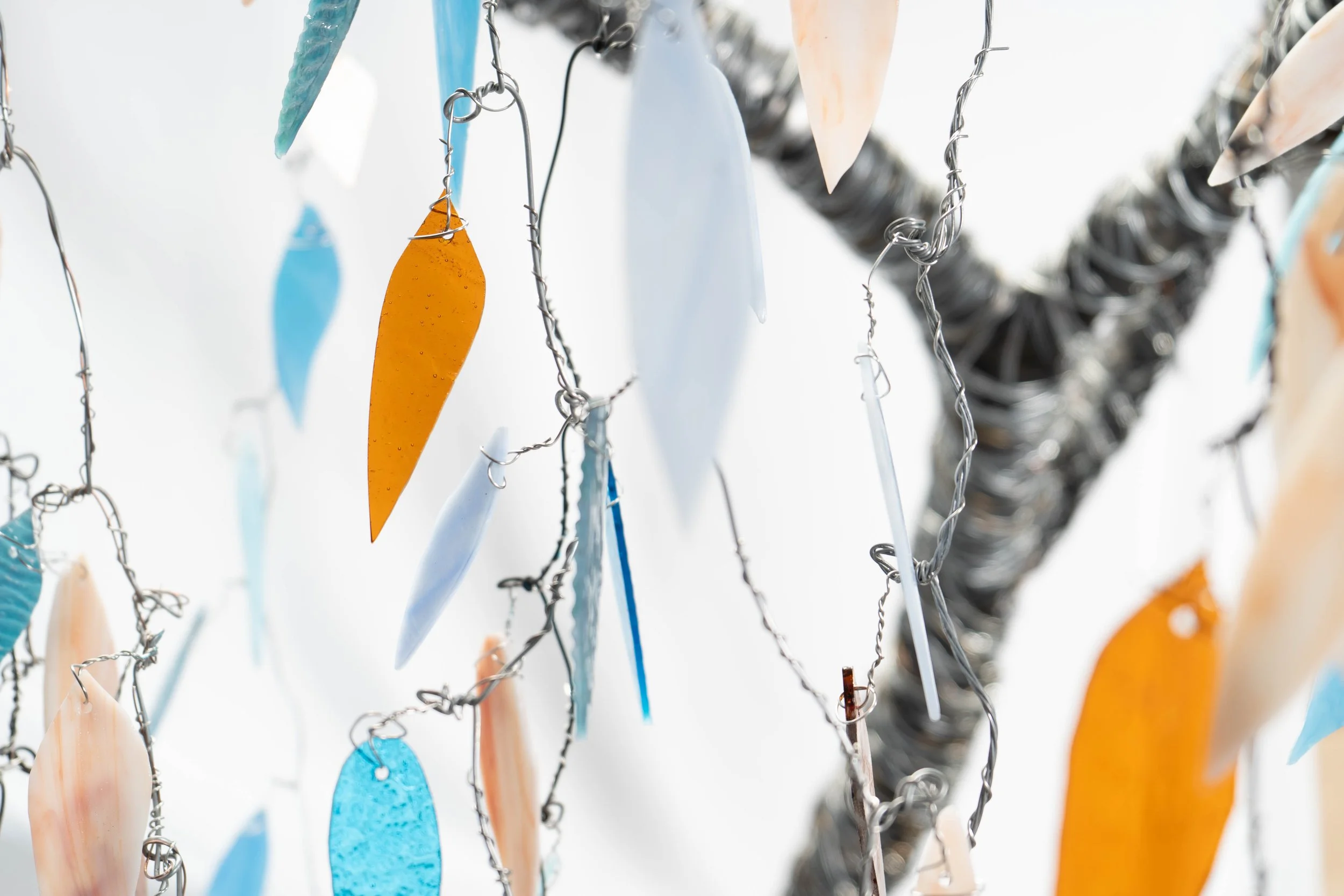 Colorful glass and metal shapes hanging from wires.