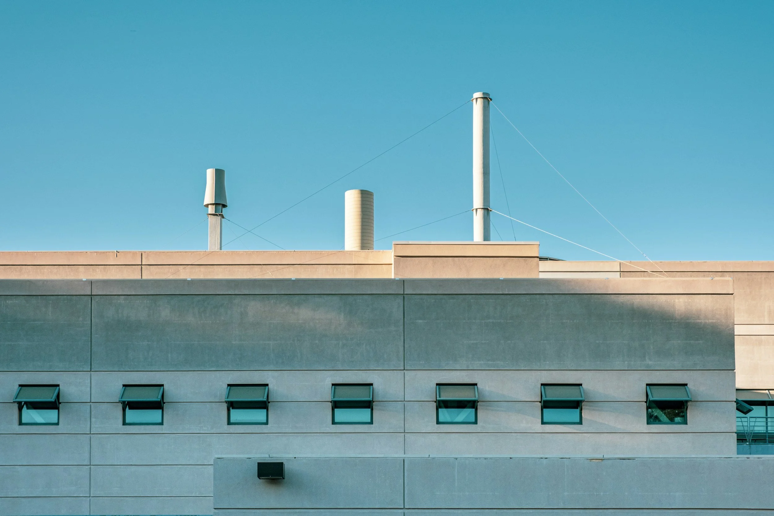 Outside view of a concrete institutional building, HVAC vents are seen on the roof