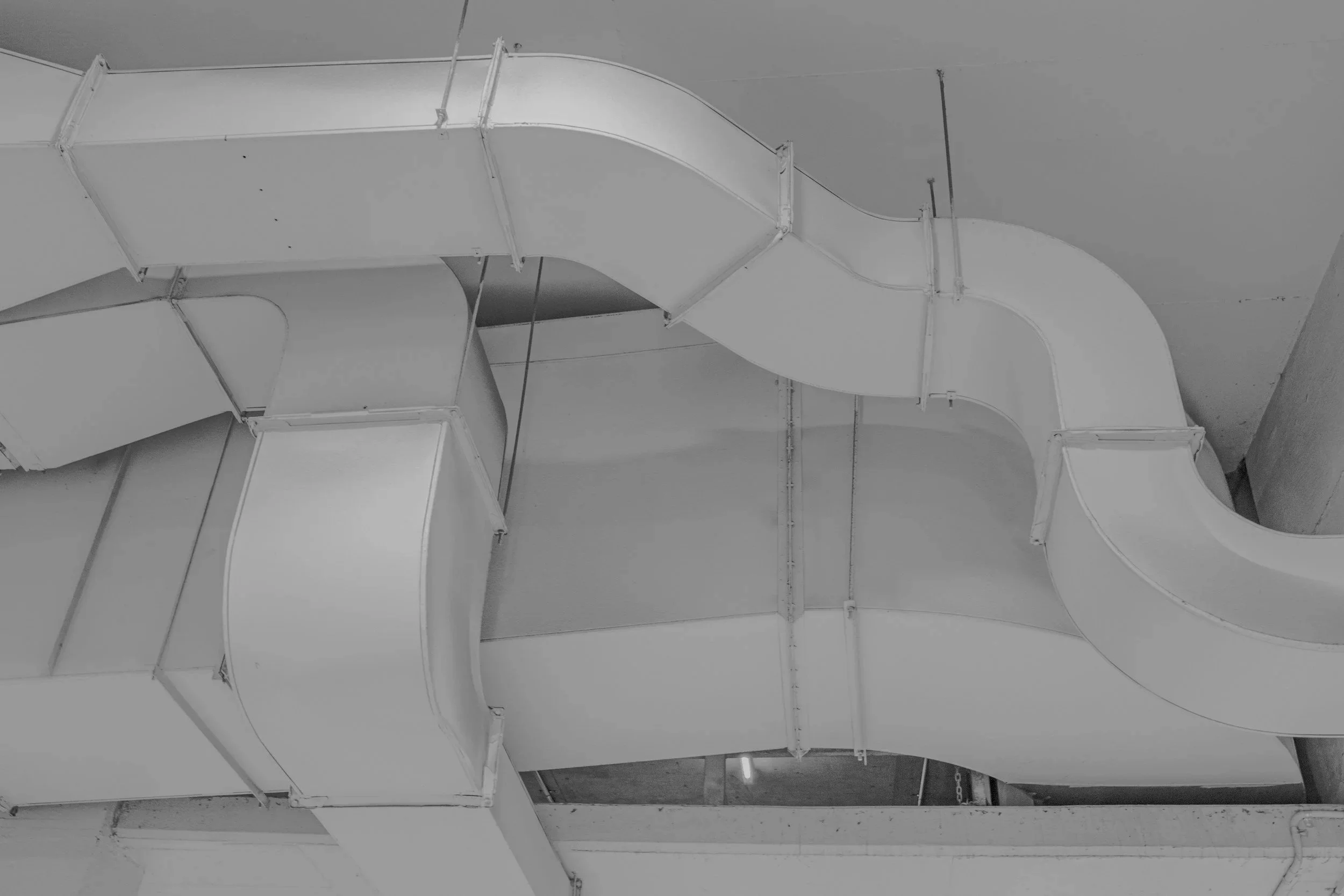 Stark white industrial HVAC ventilation shafts inside a building.