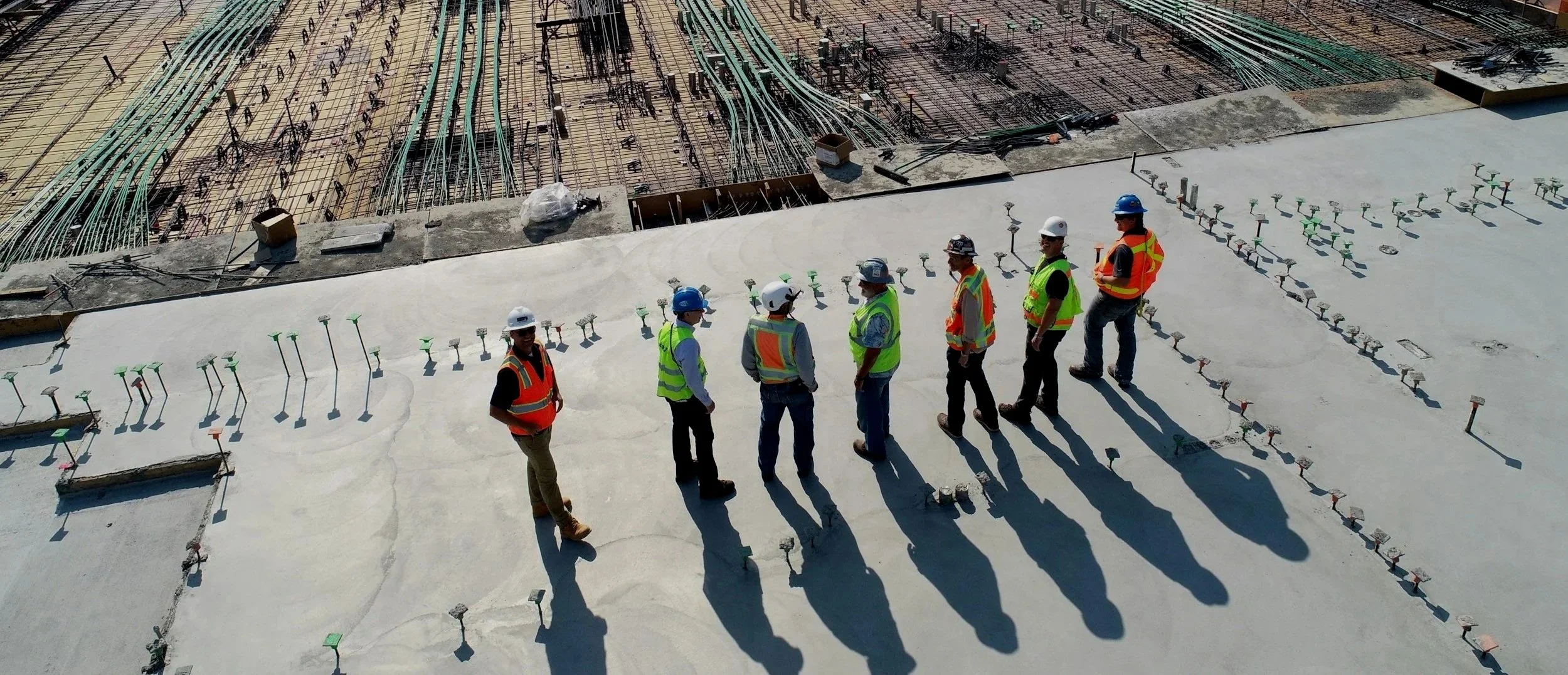 Construction workers on the foundation of an industrial job site wearing safety gear.