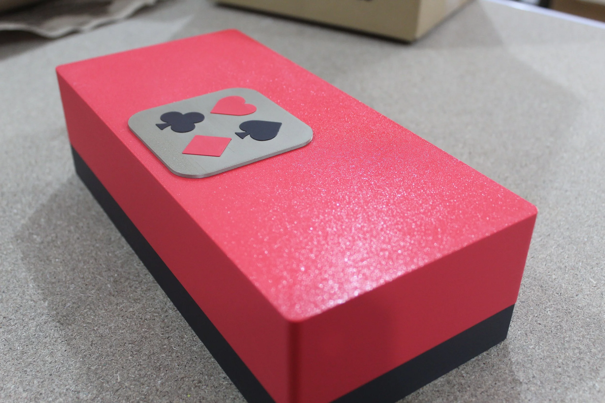 Scatola rosa con una carta da gioco decorativa raffigurante i semi di cuori, quadri, fiori di spade.