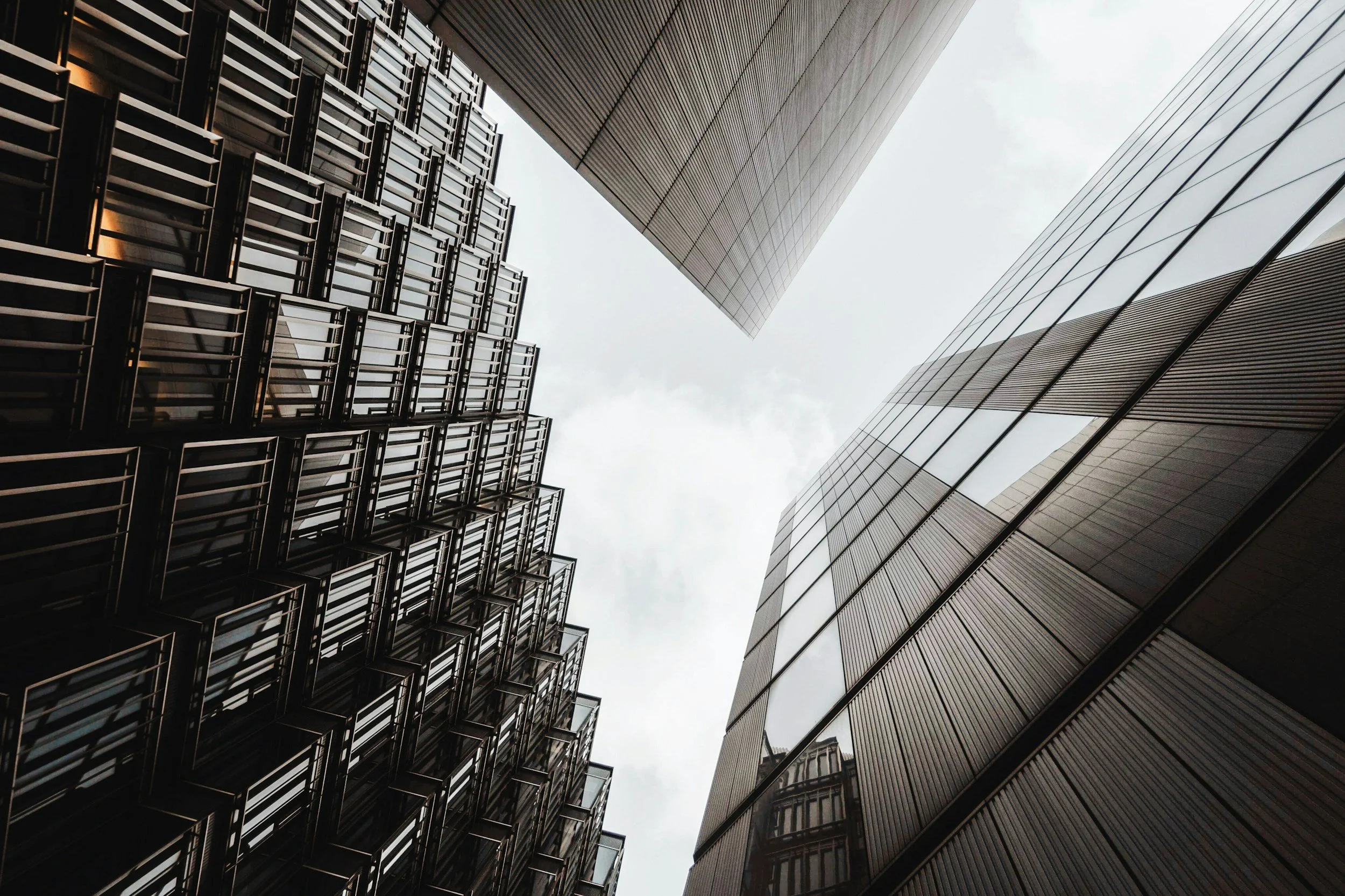 Looking up at three modern skyscrapers with glass and metal facades in a city.