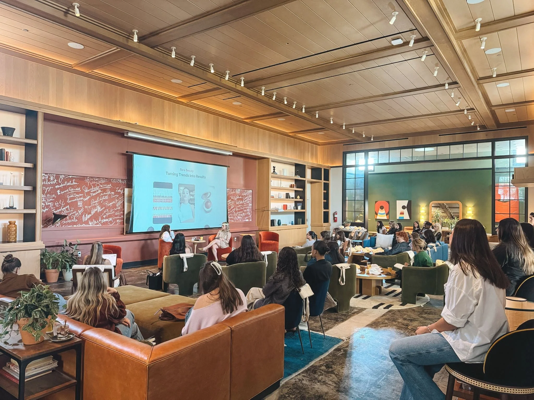 A large group of women watch a fireside chat between Daphne and another professional.