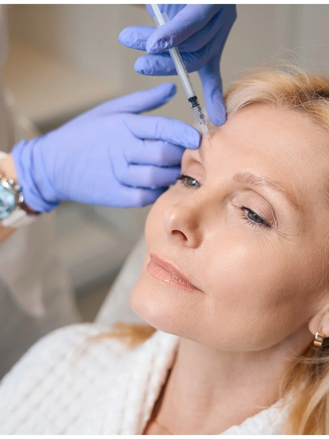 A woman receiving a cosmetic injection in her forehead from Dr Peter Forrester
