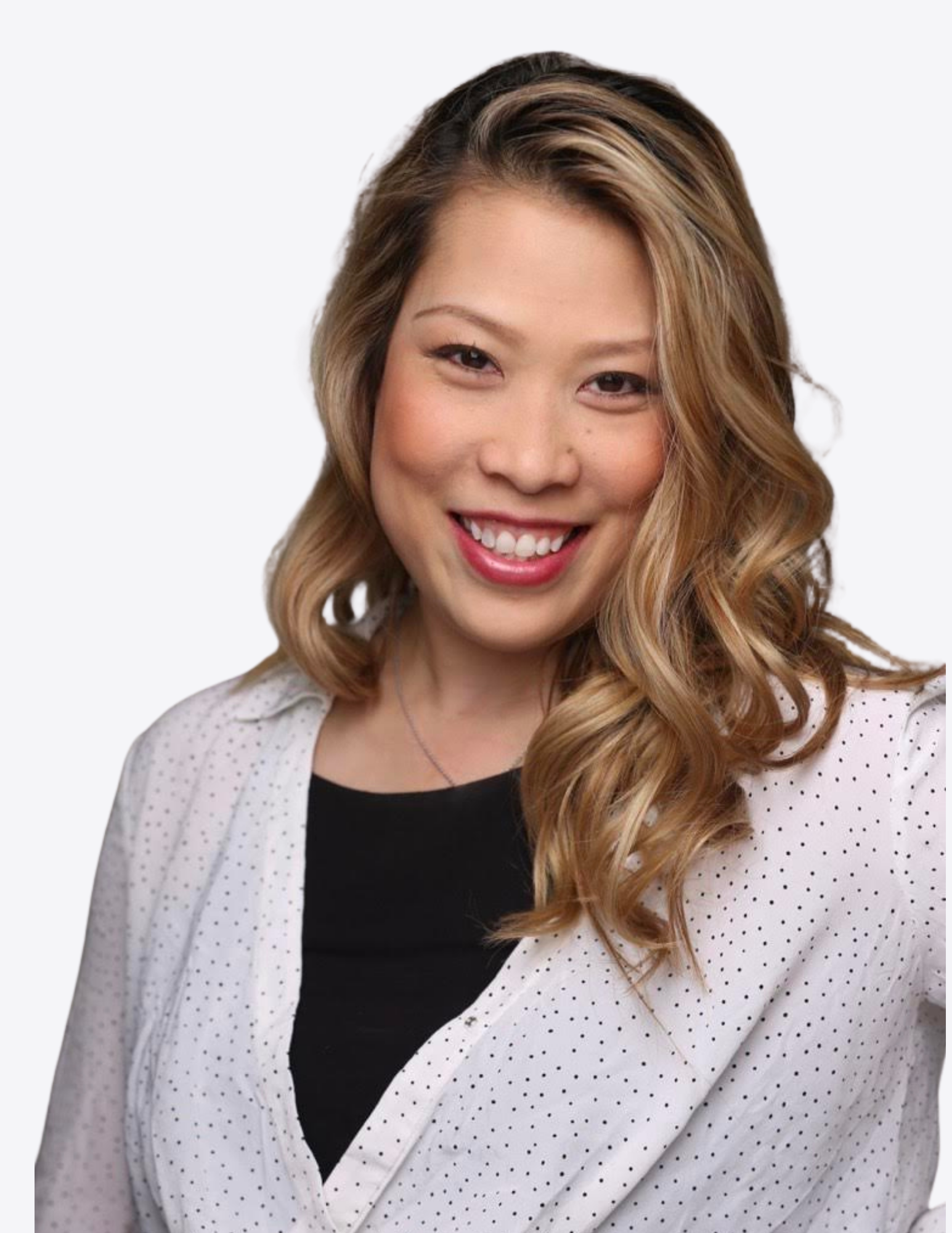 A smiling woman with wavy light brown hair, wearing a white polka-dot blazer over a black top.
