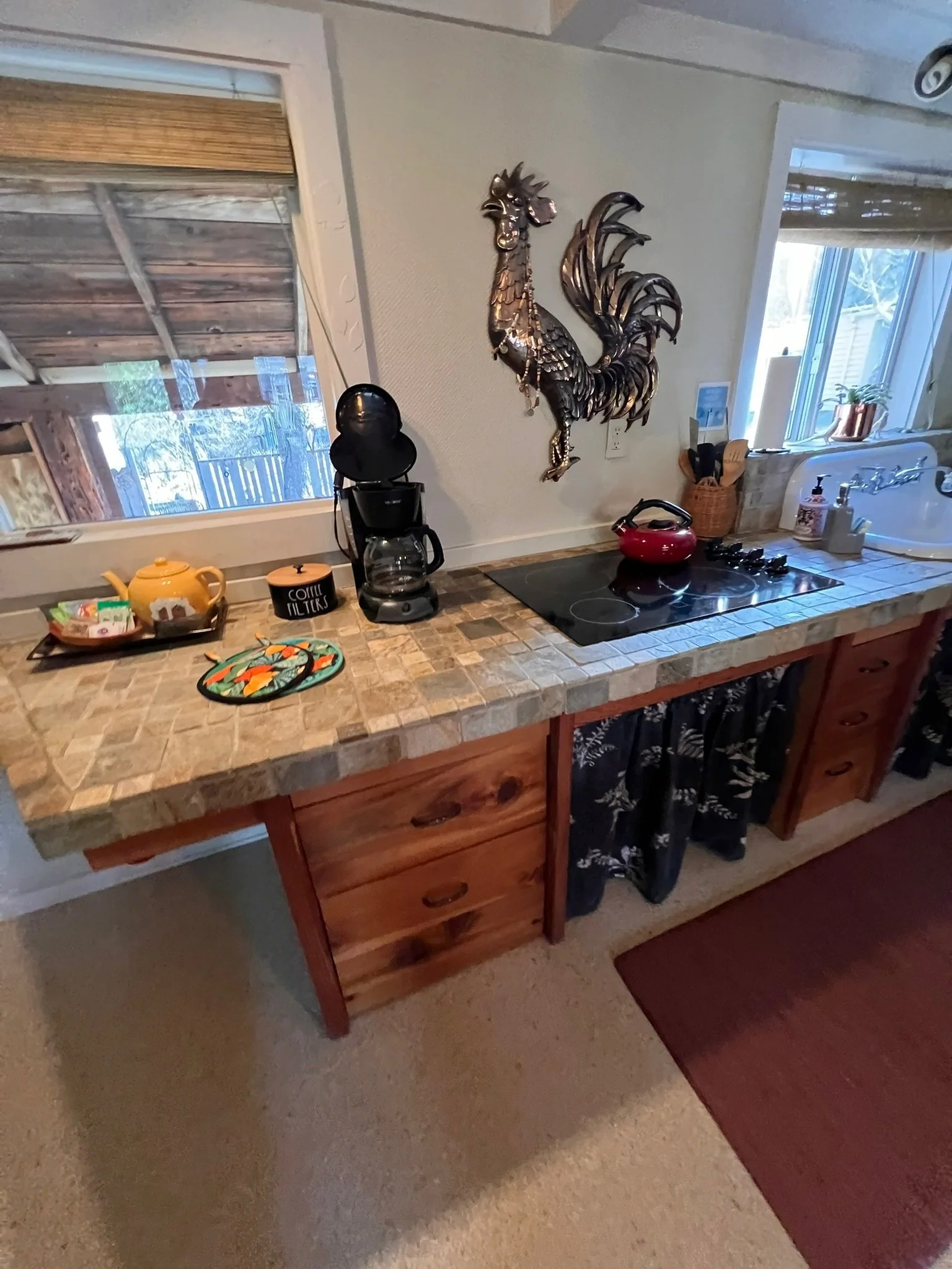 Kitchen countertop with a coffee maker, tea kettle, and decorative rooster wall art.
