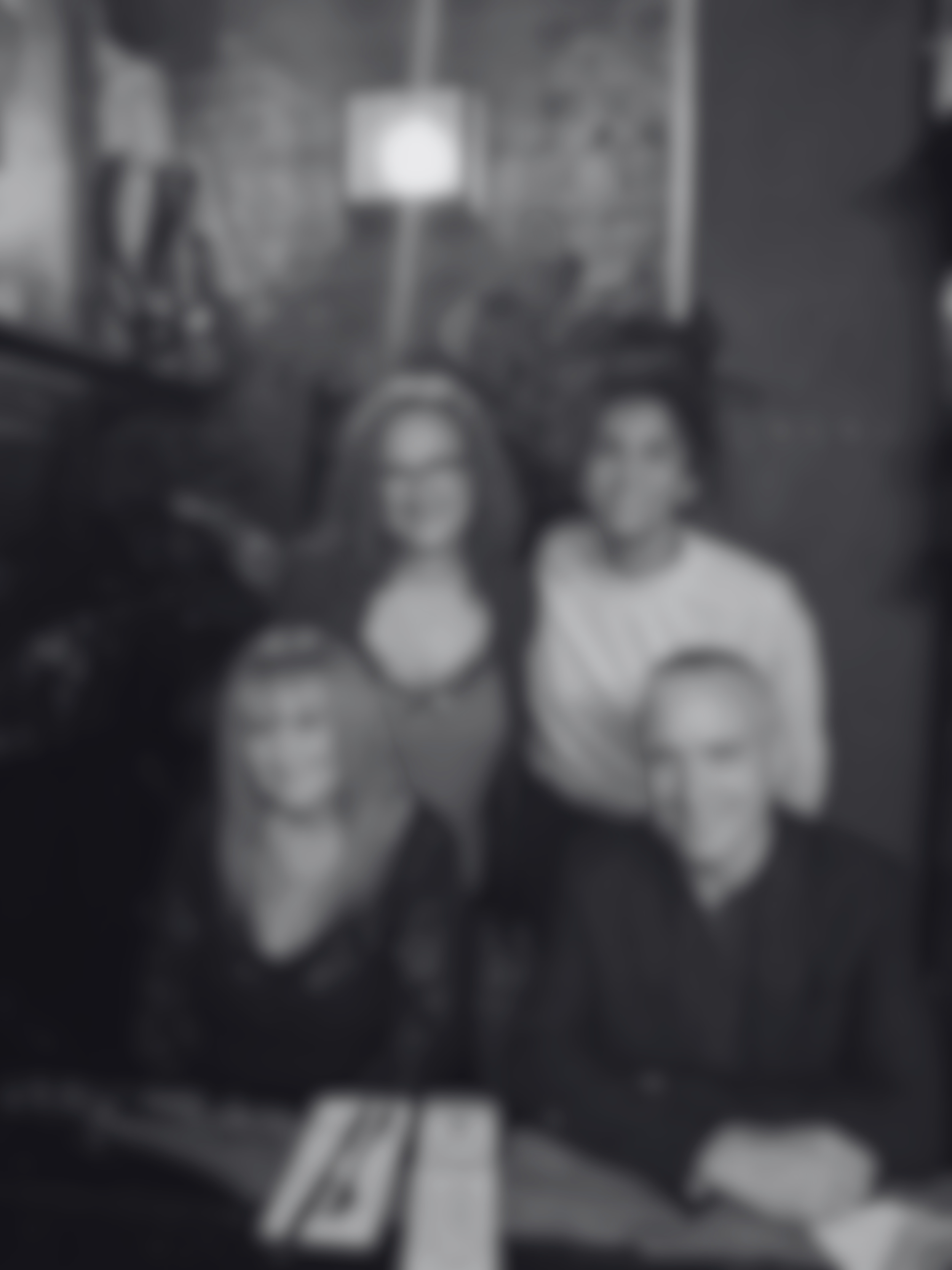 A group of five people, three women and two men, sitting together in a room with brick walls, posing for a photo.