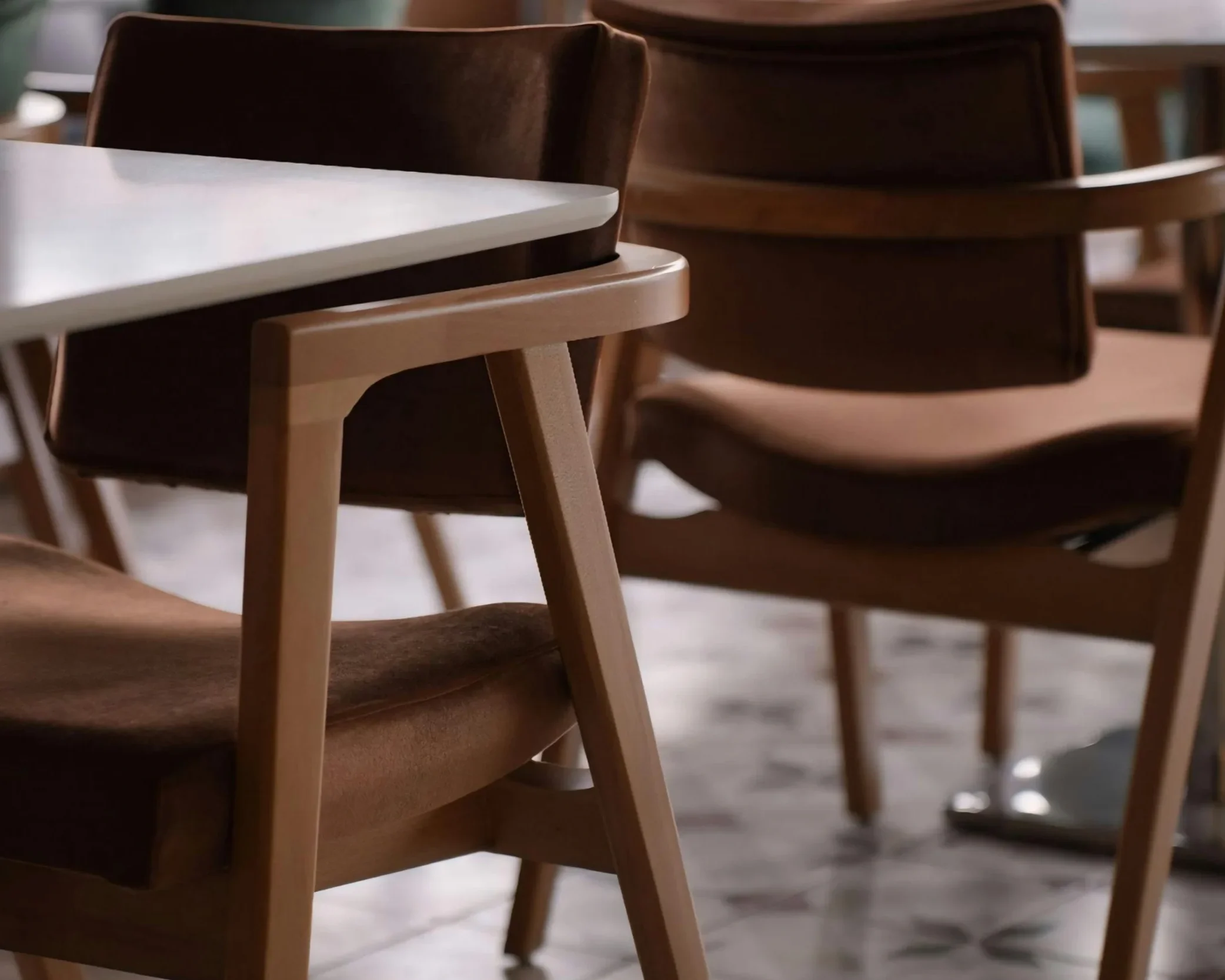 Close-up of wooden dining chairs around a white table in a café setting.