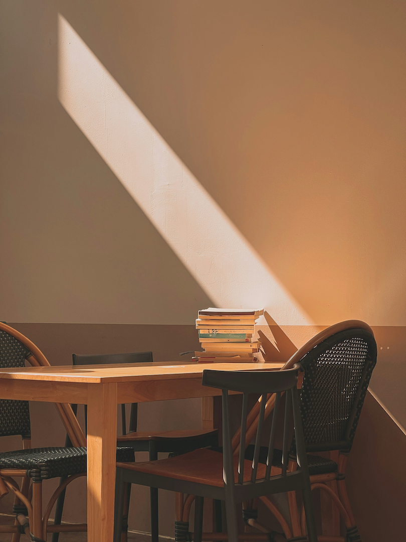 Two chairs at a table with a pile of books