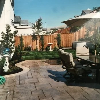 Backyard patio with outdoor furniture, umbrella, and wooden fence