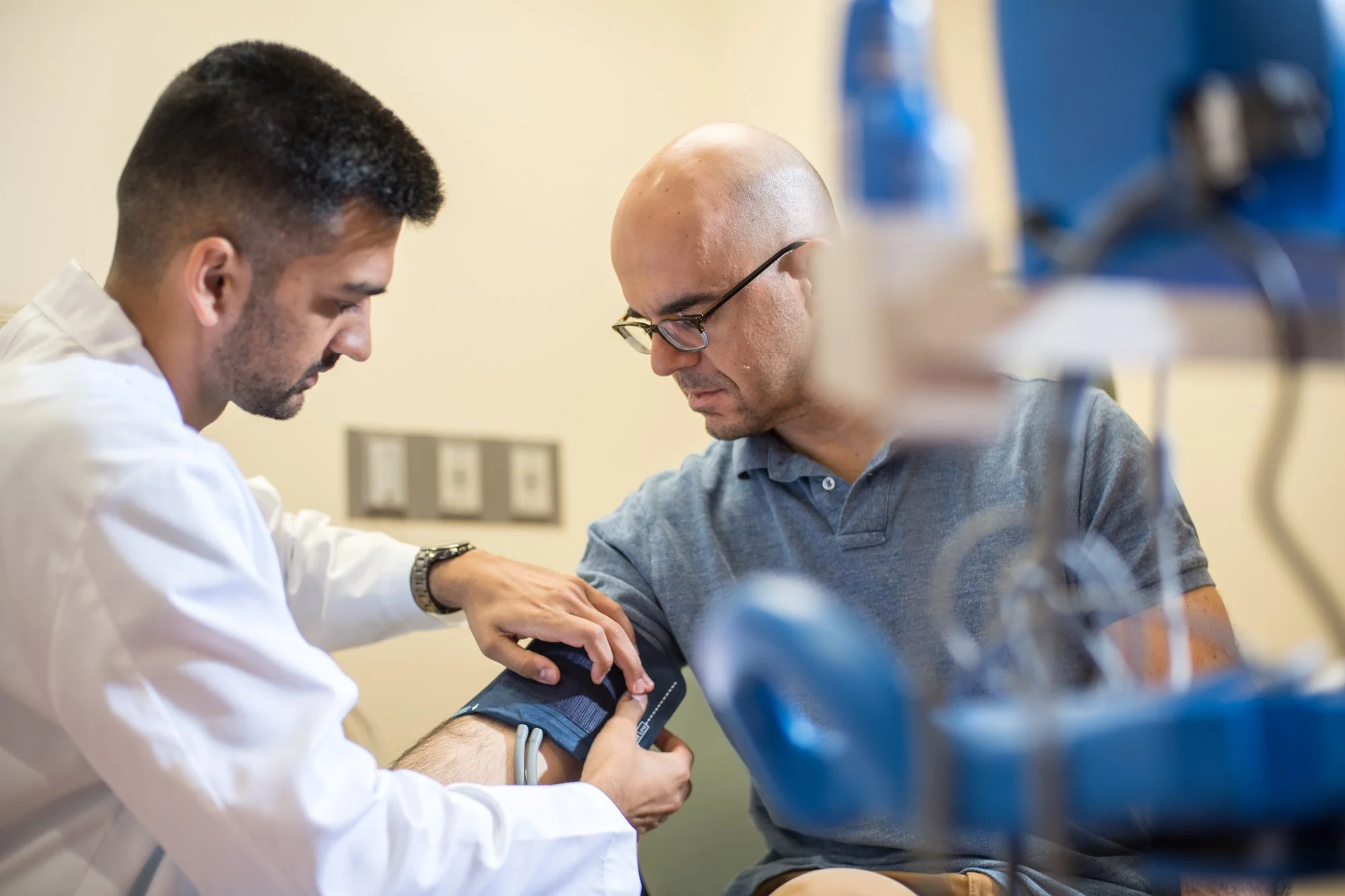 A healthcare professional measuring a patient's blood pressure using a cuff on his arm in a medical facility.