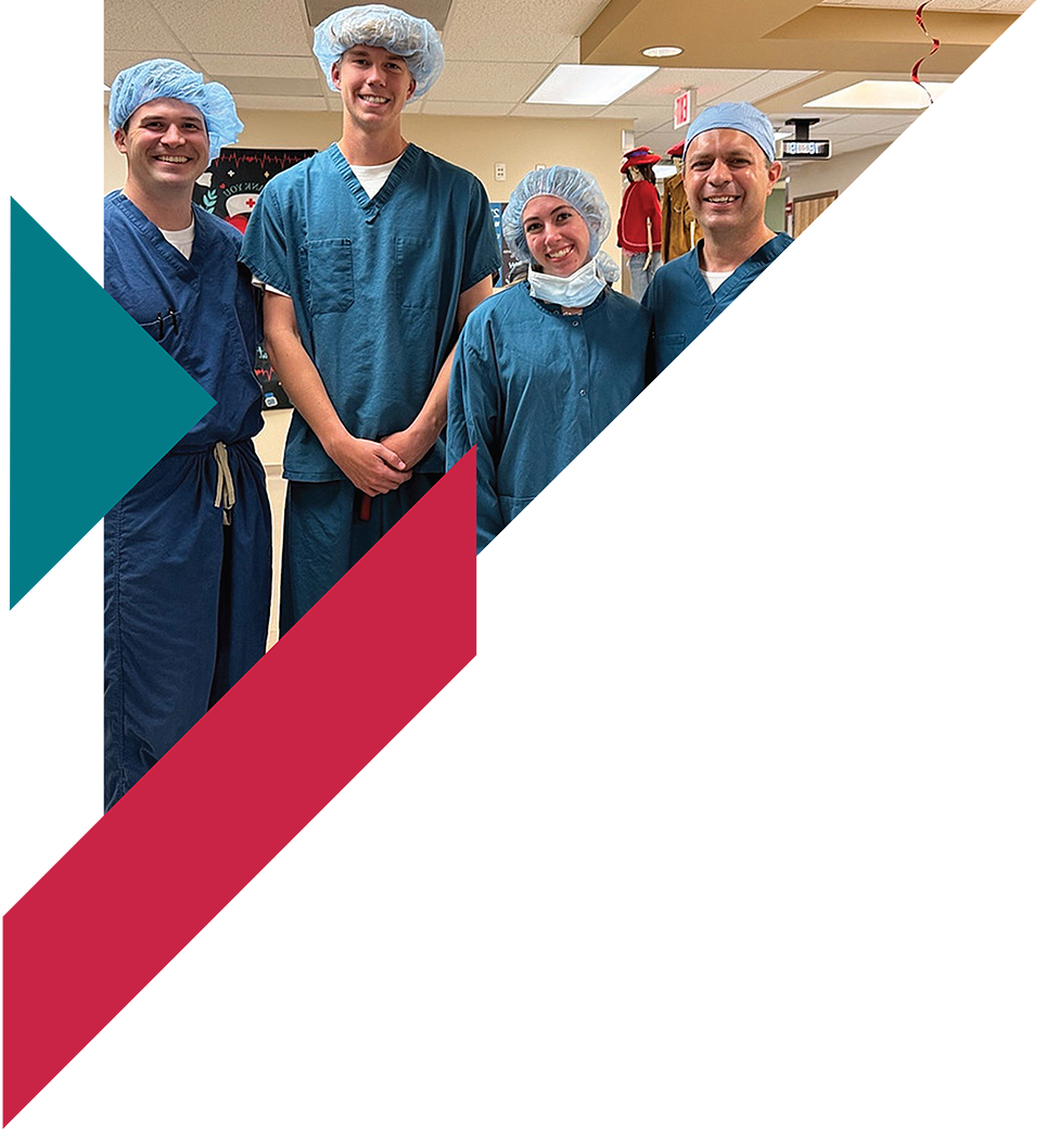 Group of four medical professionals in scrubs and surgical caps smiling in hospital setting.