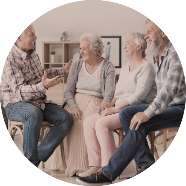 Four elderly adults sitting and engaging in conversation in a living room setting.