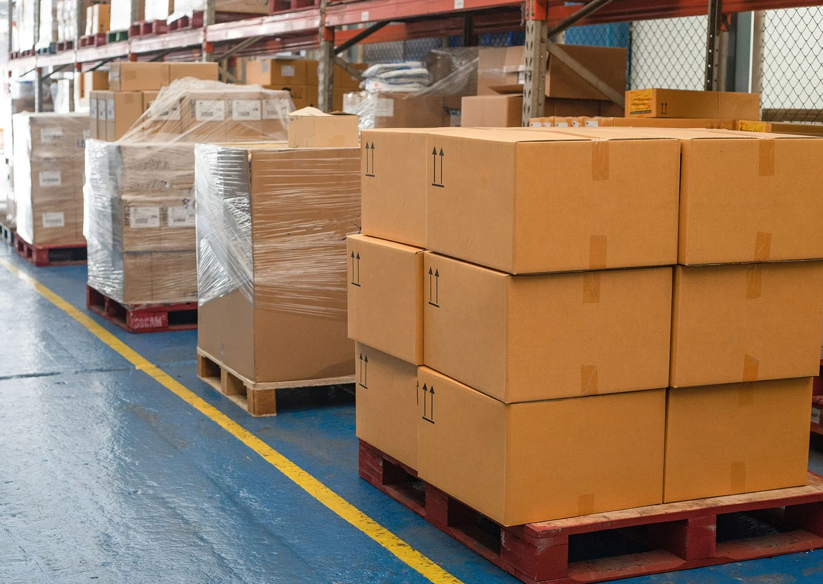 Stacked cardboard boxes on pallets at a warehouse storage area.