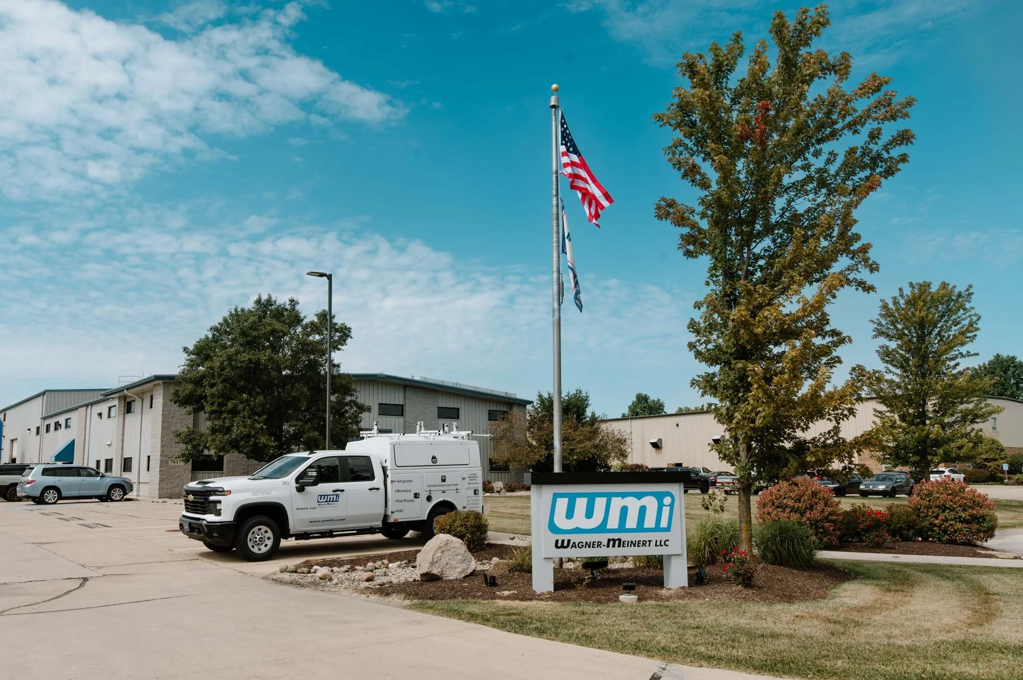 Exterior of WMI headquarters featuring their sign and a branded vehicle