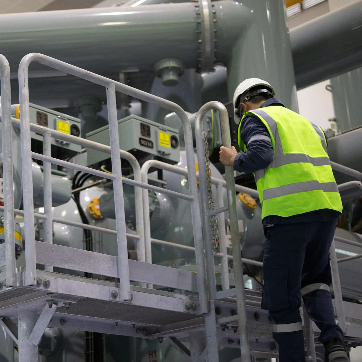A worker in safety gear inspecting equipment on a large industrial machine