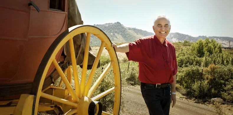 man leaning against big wheel in vineyards