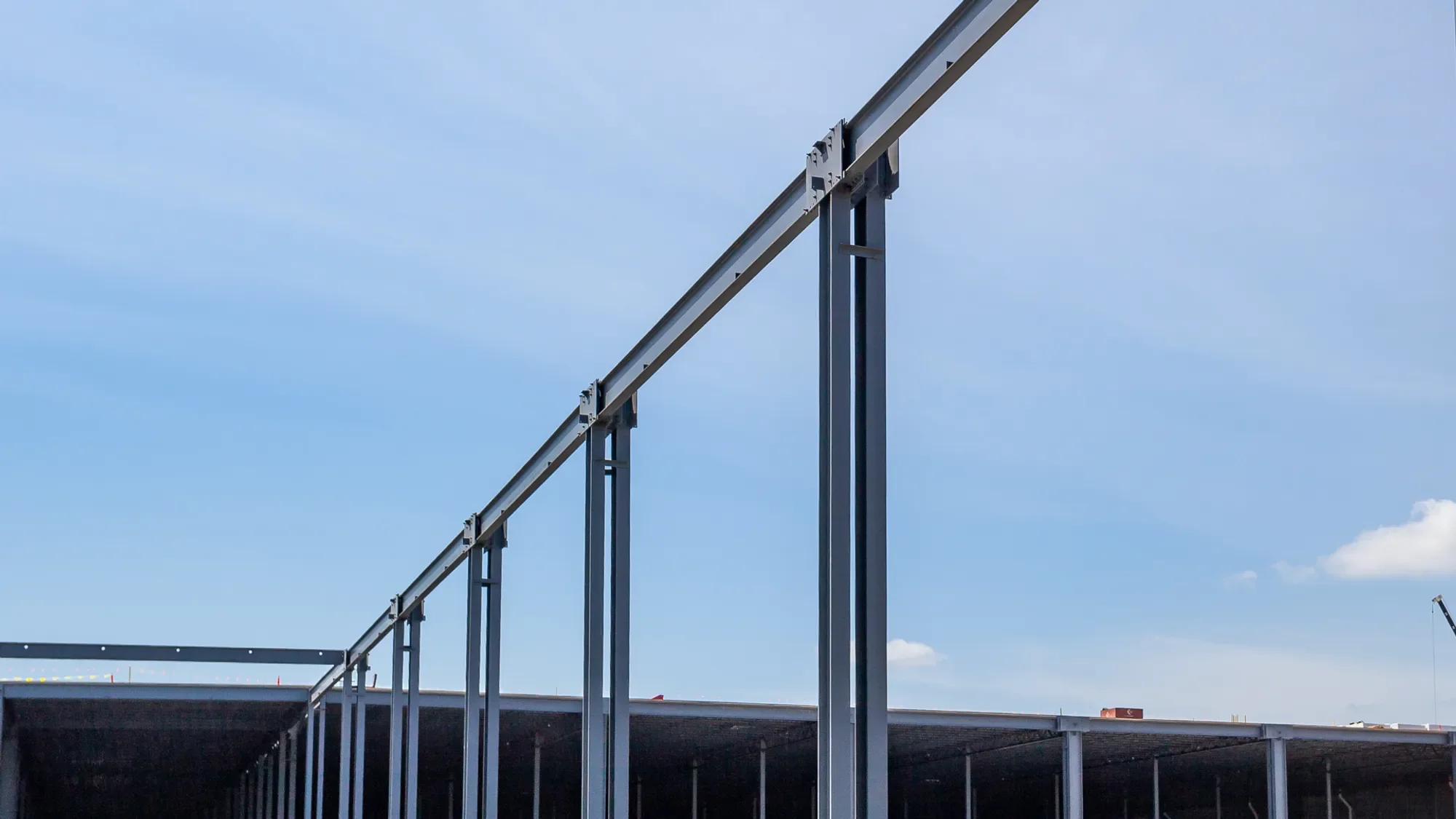 Construction site with steel framework and partial building structure under a blue sky.