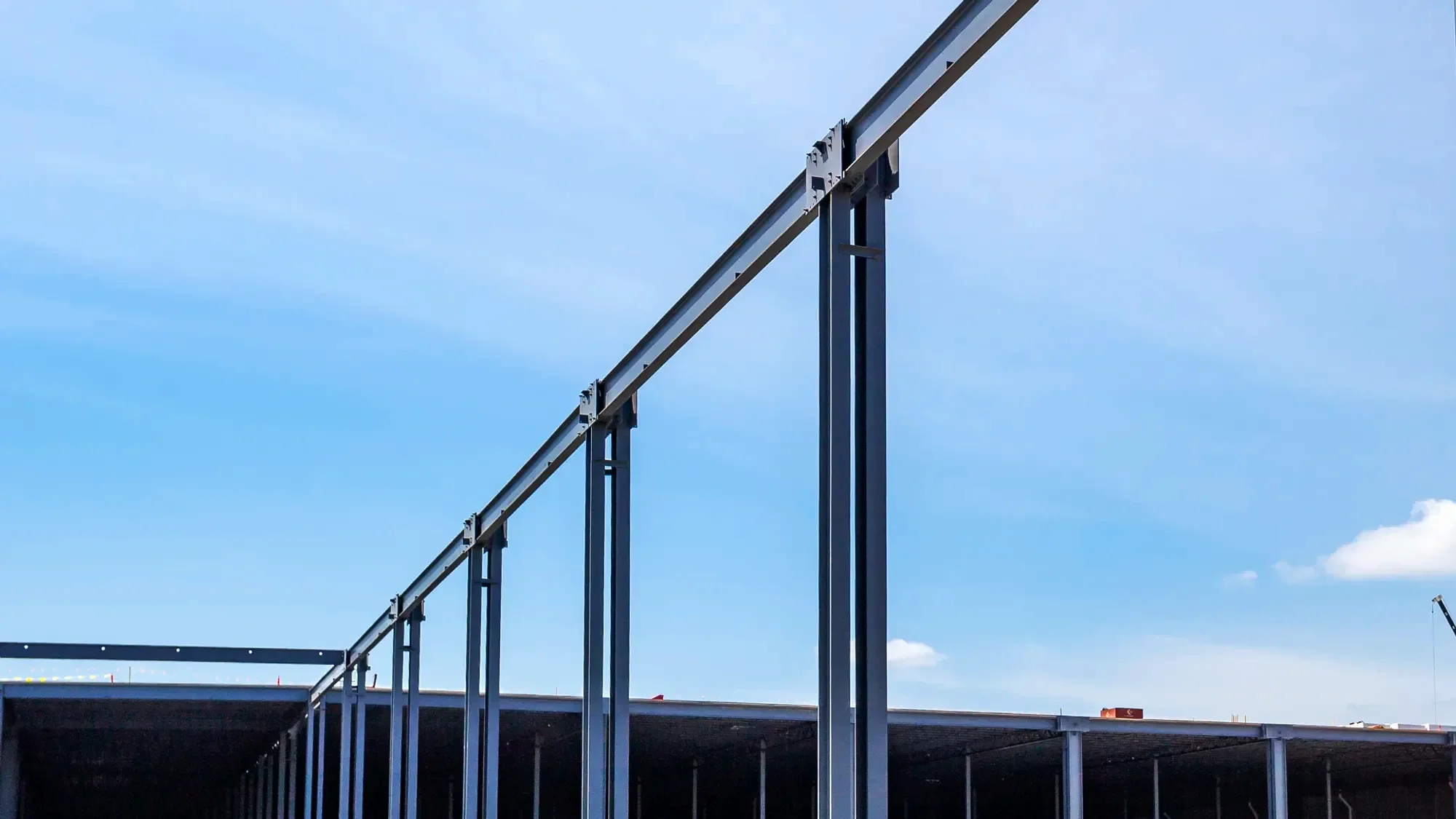 Steel framework and support beams of a building under construction against a blue sky.