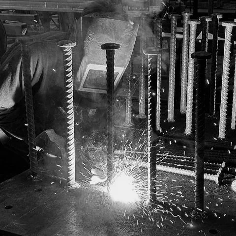 Welding process with sparks flying and metal rods set up in a workshop.