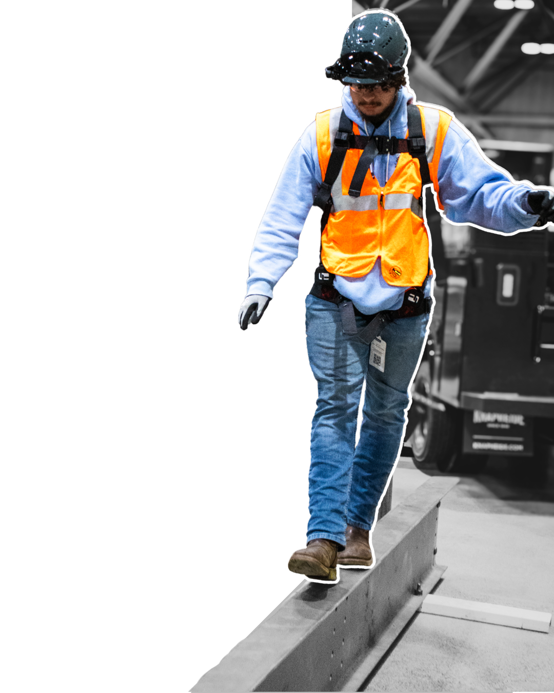 A construction worker in safety gear balancing on a wooden beam at a construction site.
