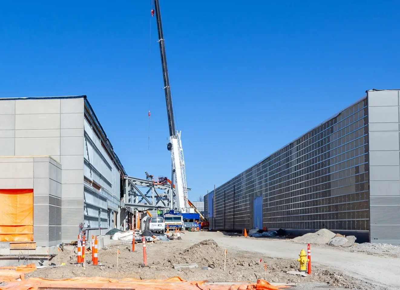 Construction site with a crane, partially built structures, and equipment under a clear blue sky.