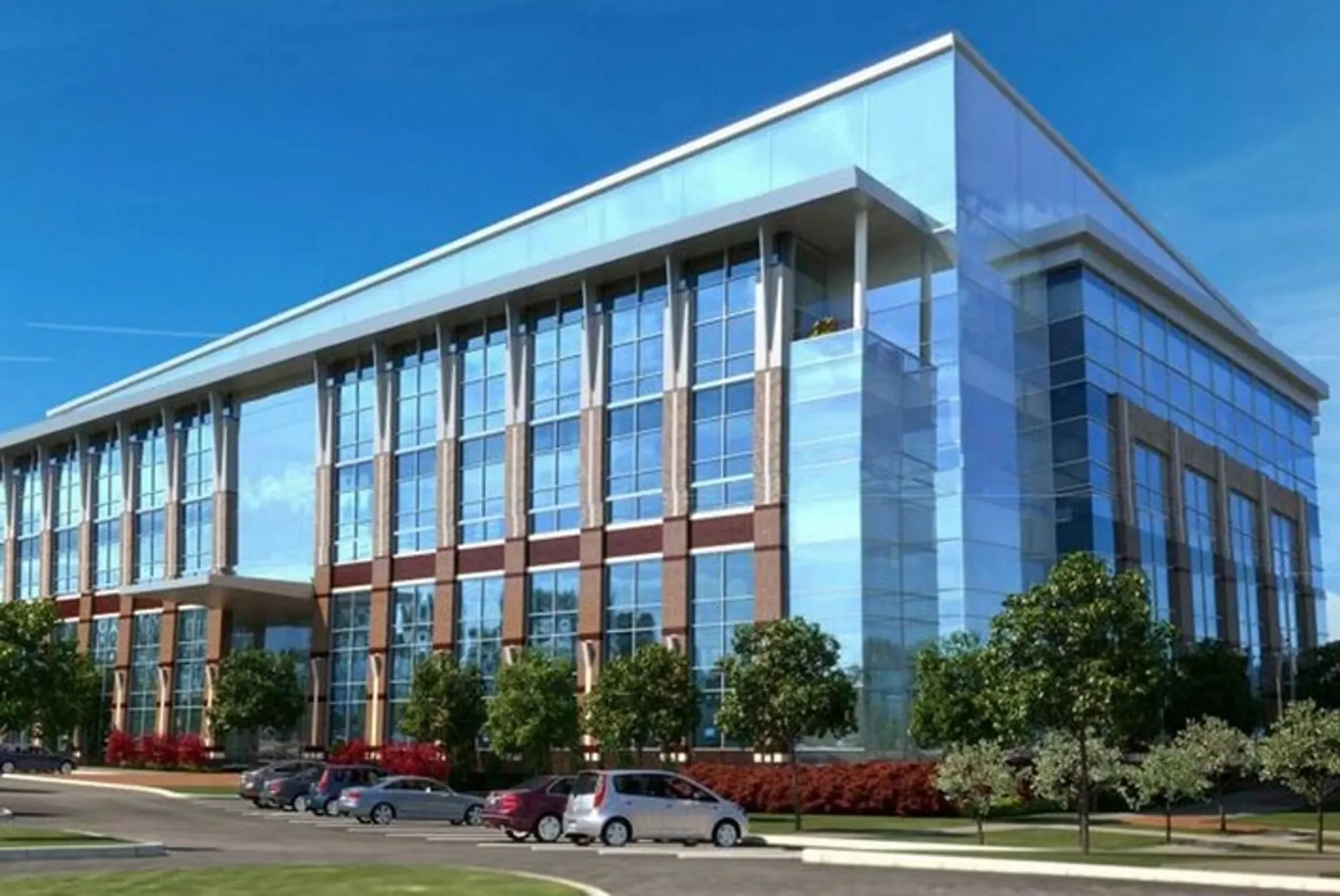 Modern multi-story office building with glass windows and brick accents, surrounded by parking lot and trees, under a blue sky.