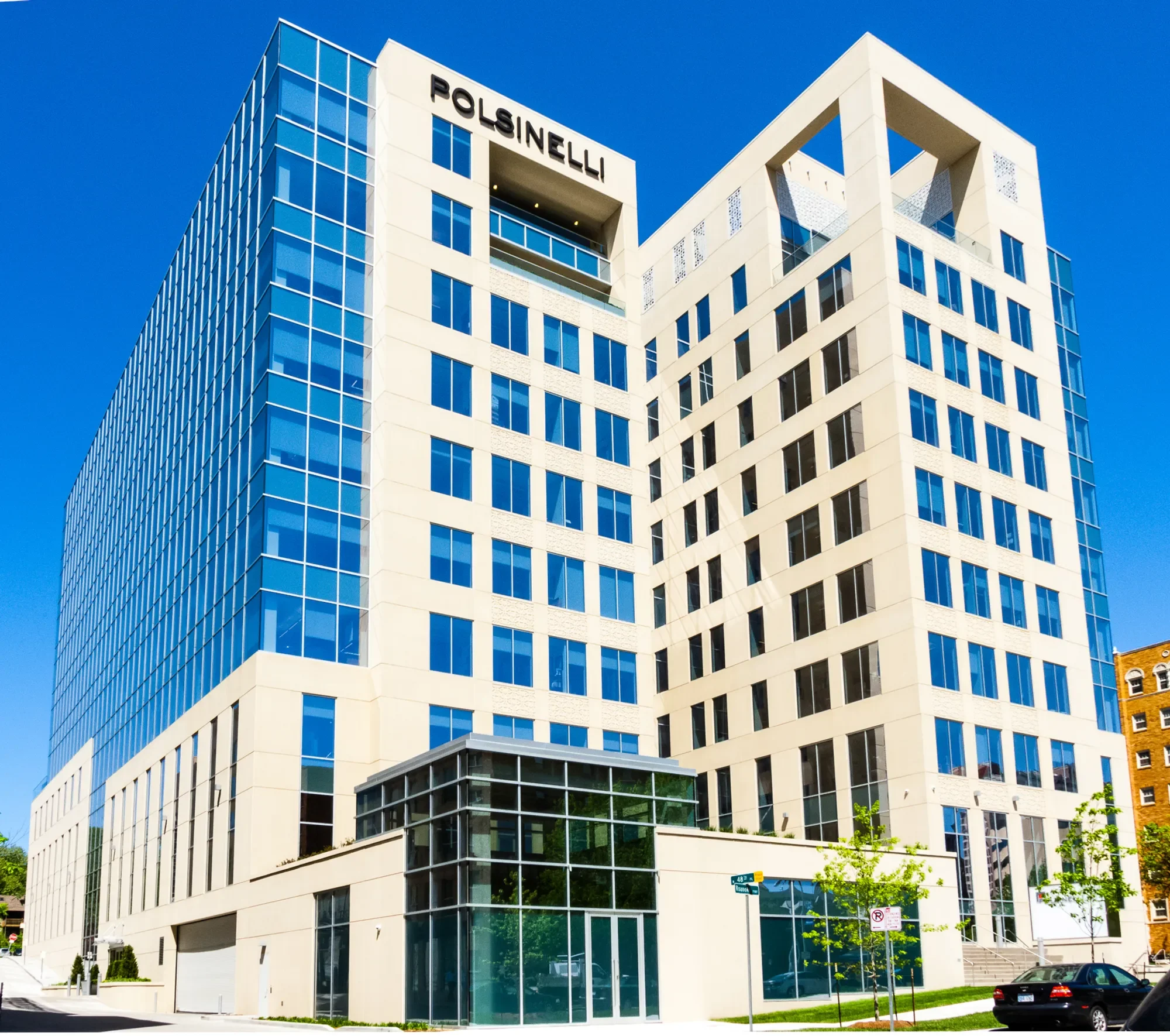 Modern white apartment building with glass windows and balcony openings under a clear blue sky.