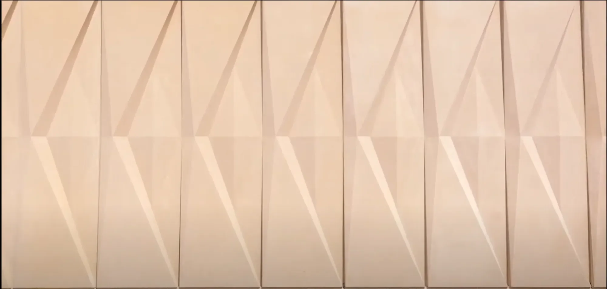 Close-up of a beige wall with geometric patterns consisting of diagonal lines and triangles.