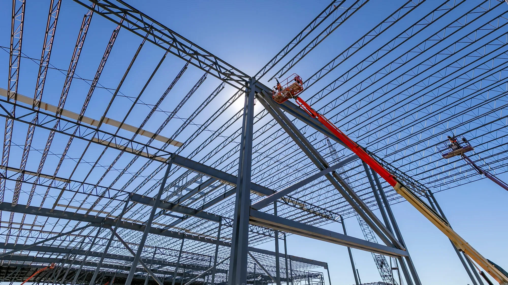 Steel framework of a building under construction with two lifts and workers.