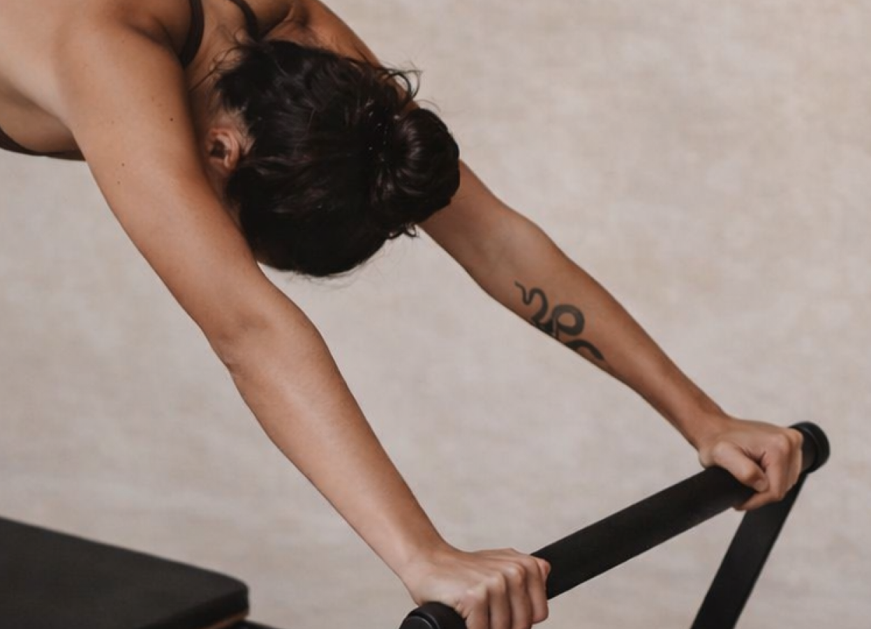 Woman performing a plank variation on the Megaformer at Form Haus Lagree studio, Seaford NY