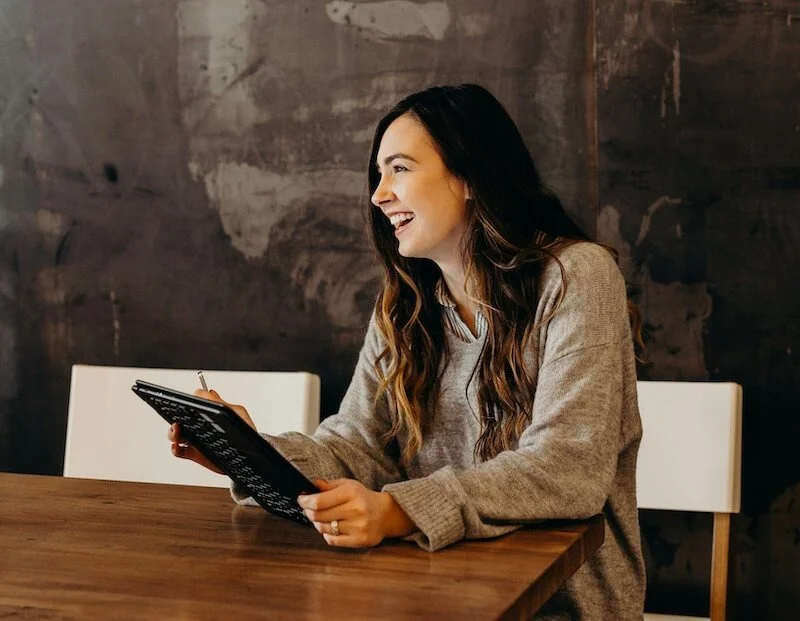 Junge Frau lächelt beim Lesen eines Buches in einem Café.