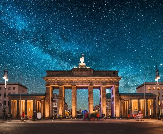 Das Brandenburger Tor bei Nacht unter einem Sternenhimmel mit der Milchstraße sichtbar.