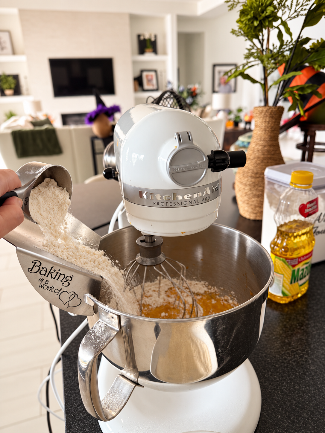 Hand pouring flour into a KitchenAid bowl.png