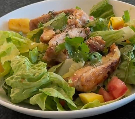 mango, parsley, chicken, lettuce in a white bowl