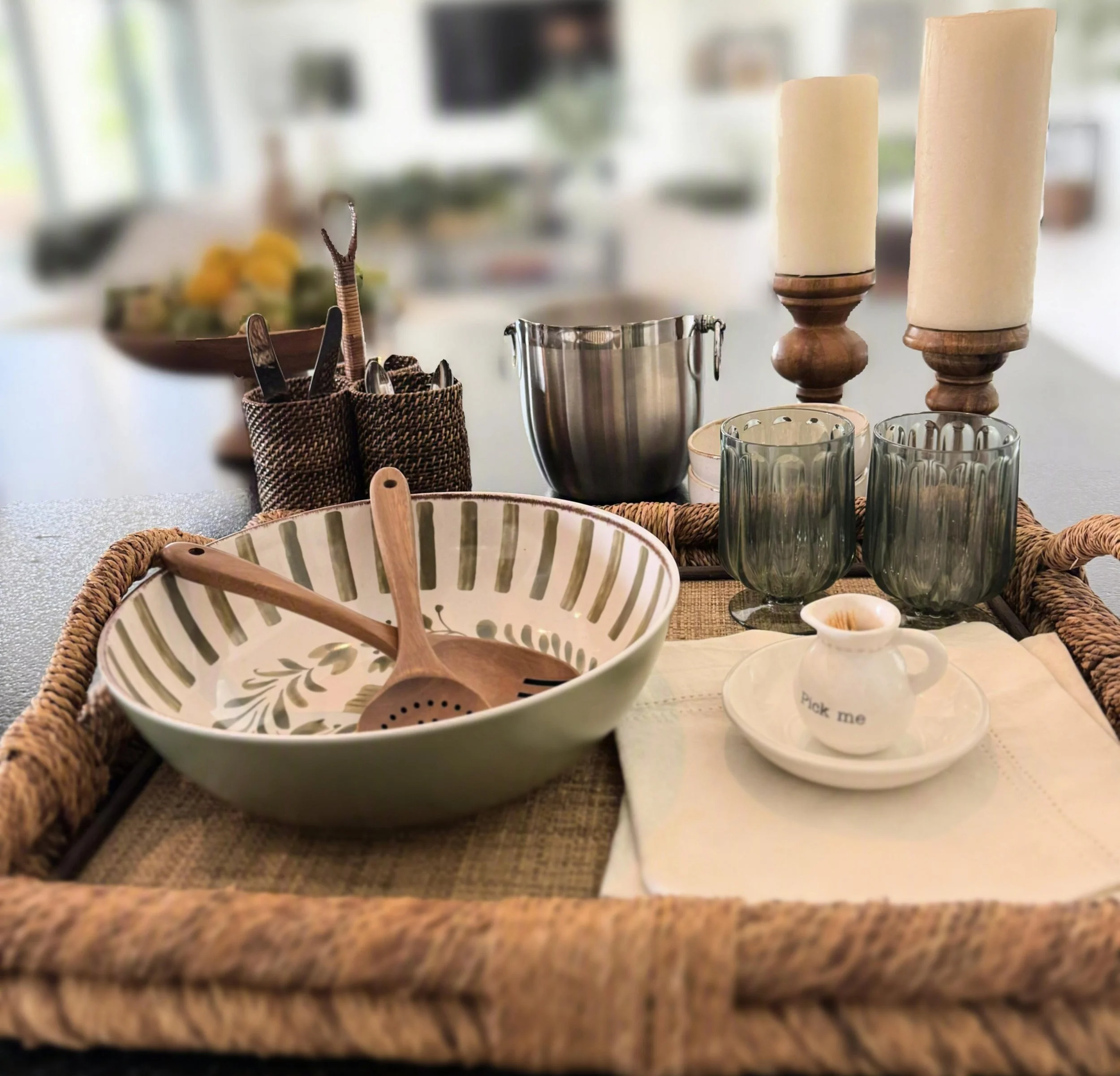 Woven patio serving tray with appetizer dishes, outdoor glasses, linen napkins, an ice bucket, and candles.