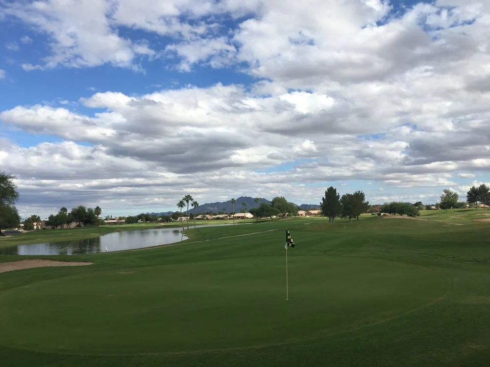 Green fairway and pond at Springfield Golf Resort in Chandler, Arizona under a partly cloudy sky