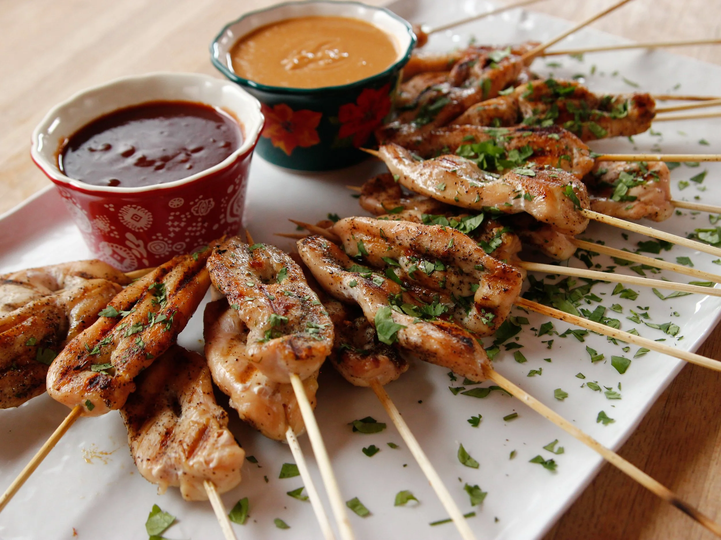 Grilled chicken skewers served with peanut and barbecue dipping sauces.