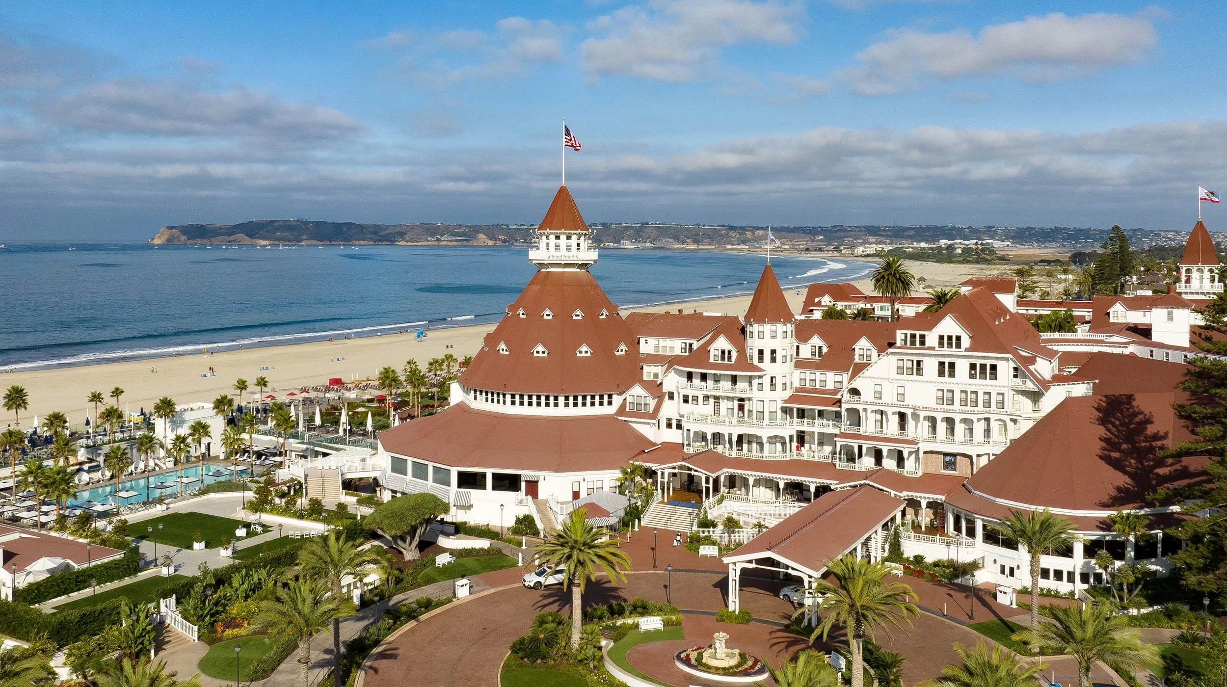 Aerial view of Hotel del Coronado with red rooftops, beach, and ocean views.