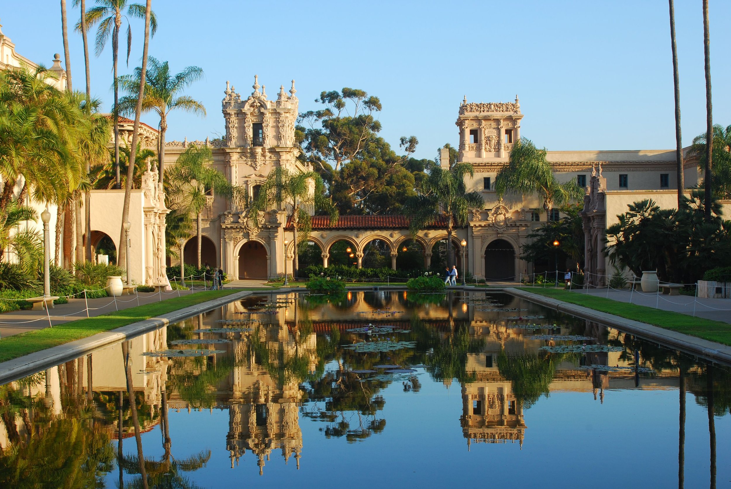 Balboa Park reflecting pool with historic Spanish-style architecture and palm trees.