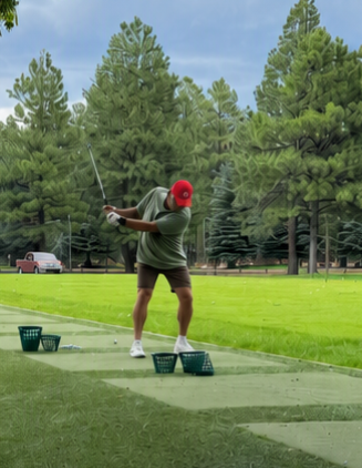Golfer swinging at the driving range surrounded by tall pines at Pinetop Lakes Golf & Country Club