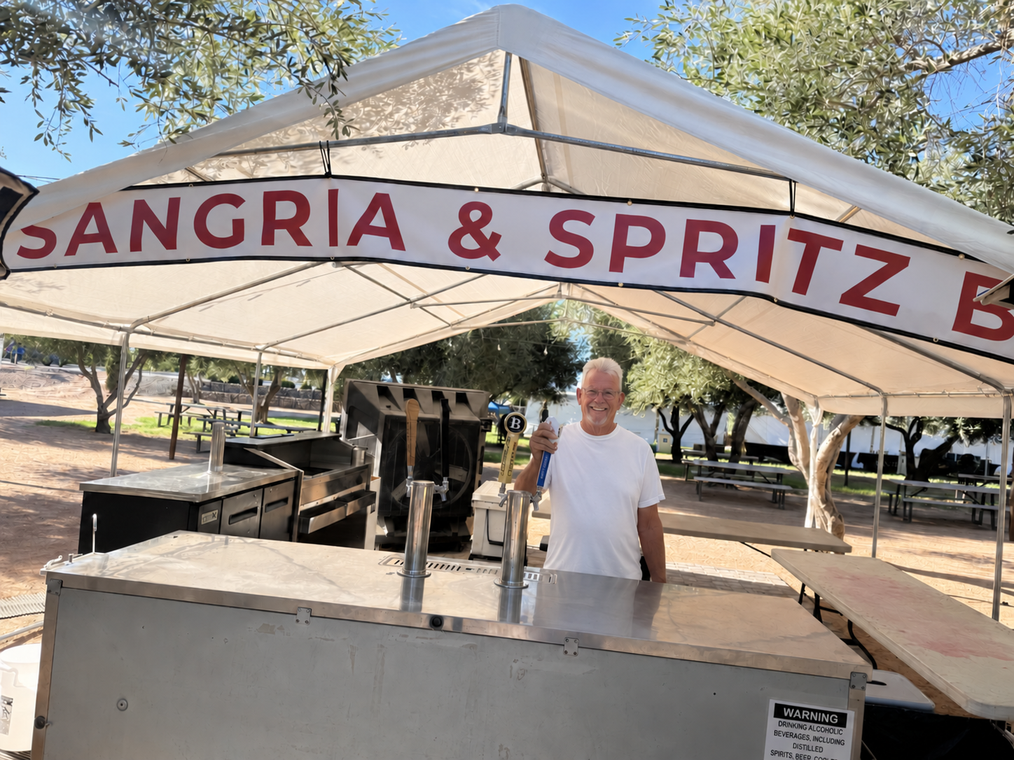 Johnny B smiling behind the Sangria and Spritz bar during the Queen Creek Olive Mill Garlic Festival.