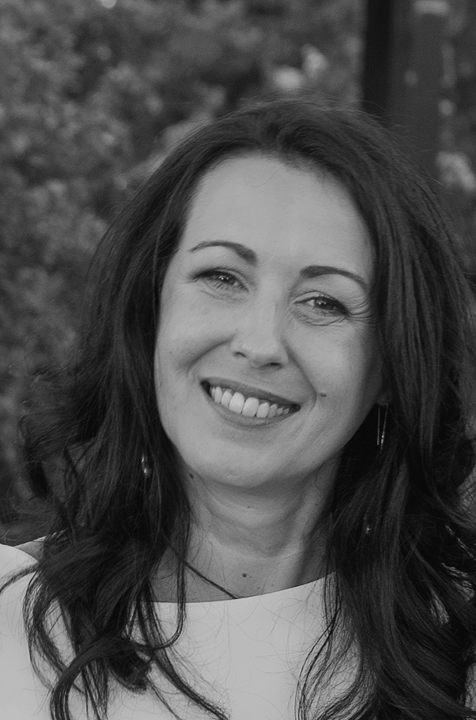Portrait en noir et blanc de Patricia Prodel, Artiste Dessinatrice et Plasticienne souriant avec des cheveux longs et bouclés, en extérieur.