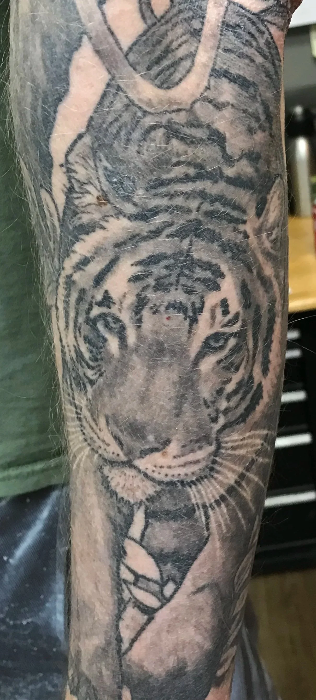 Black and gray tattoo of a tiger's face on a person's arm.