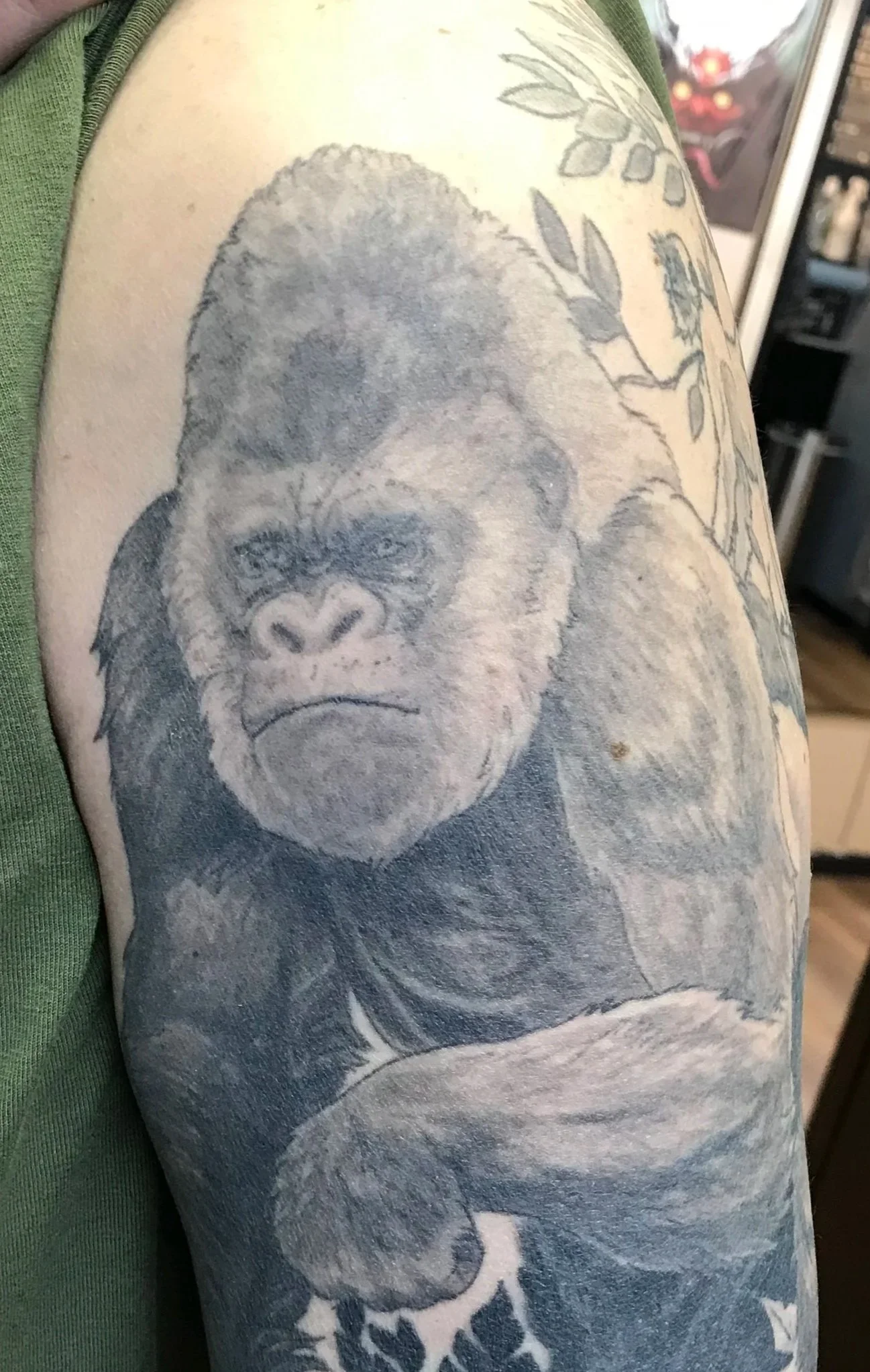Close-up of a tattoo on a person's arm featuring a detailed gorilla face and floral design.