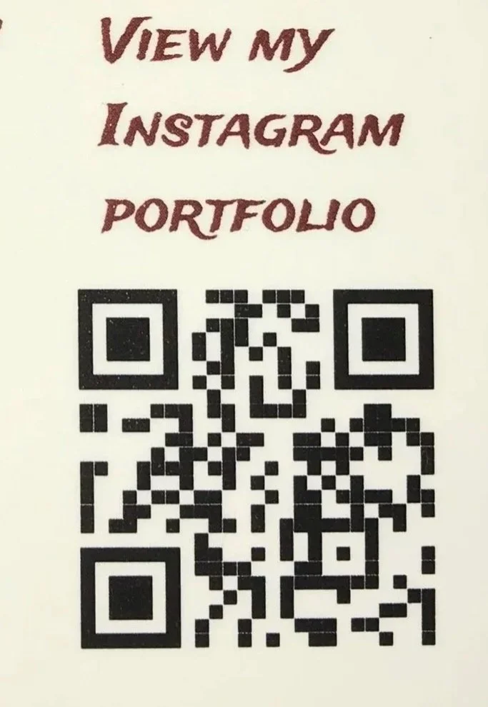 A handwritten sign with the text 'View my Instagram portfolio' above a QR code.