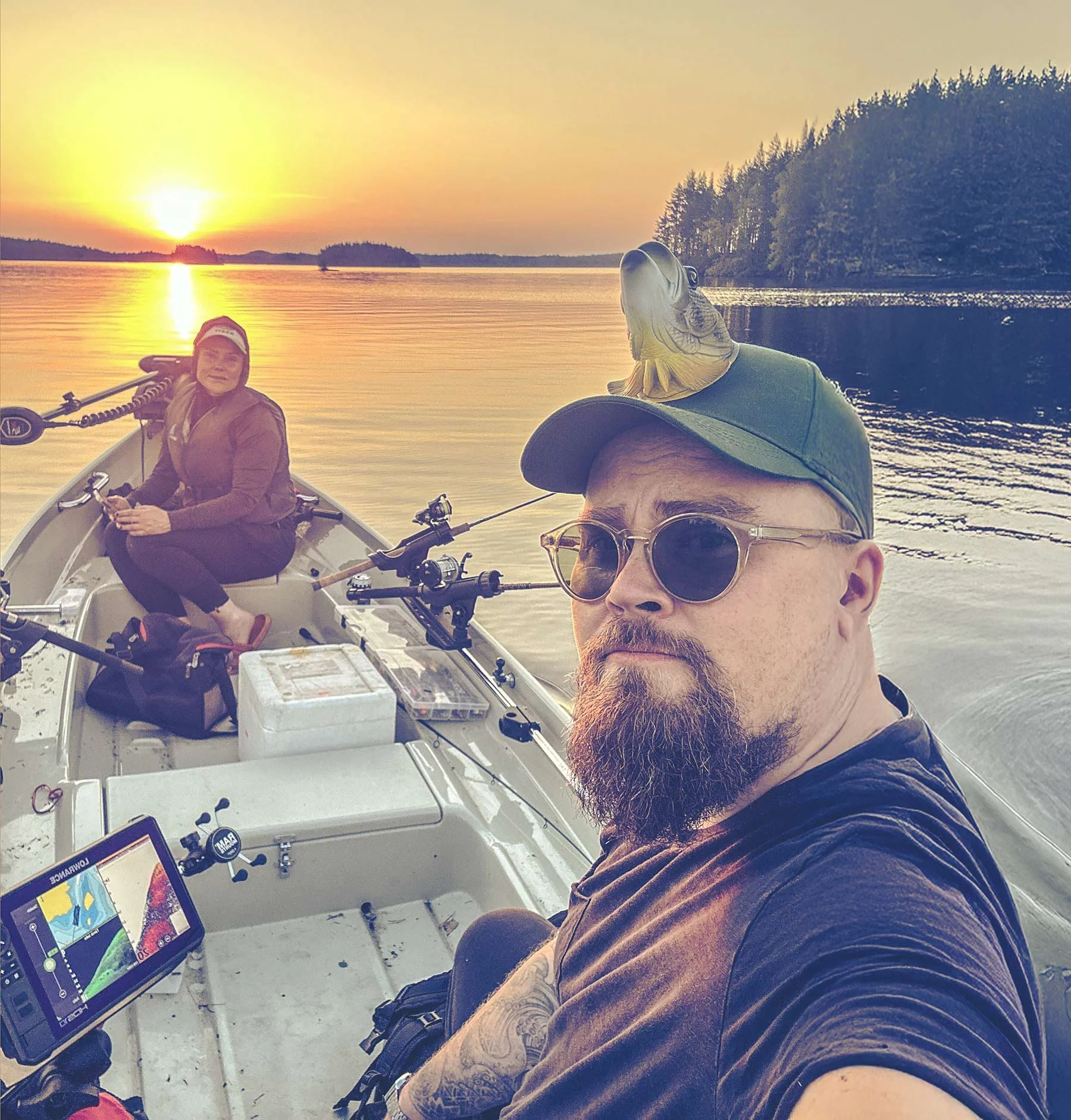 Kaksi ihmistä on veneessä iltauinnin aikana Costa Rica -saaren rannikon auringon laskiessa. Yhden ihmisen siluetti näkyy otsalamppu, sarven ja aurinkolasien kanssa, ja toinen mies katsoo kamerapäin